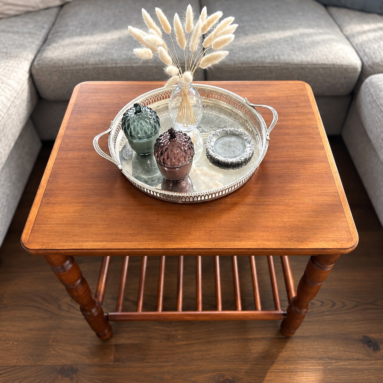Silver tray with glass objects and dried grasses on an older wooden coffee table