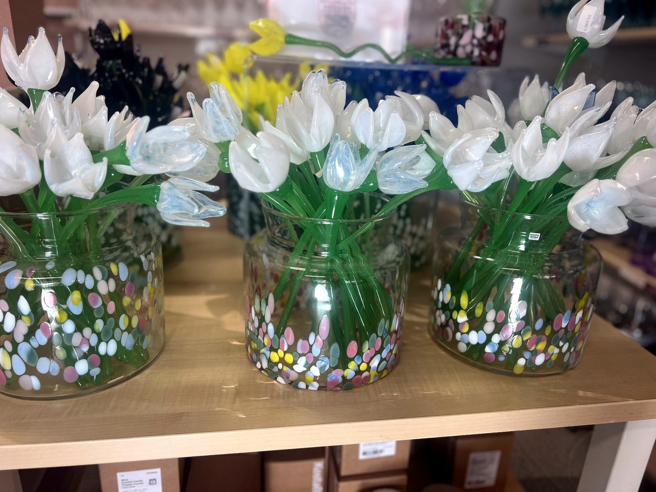 Shelf of glass vases filled with white and yellow glass tulips