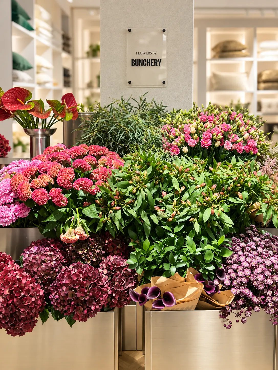 Floristdelen Flowers by Bunchery med metallkärl fulla av snittblommor i H&M HOME:s butik.